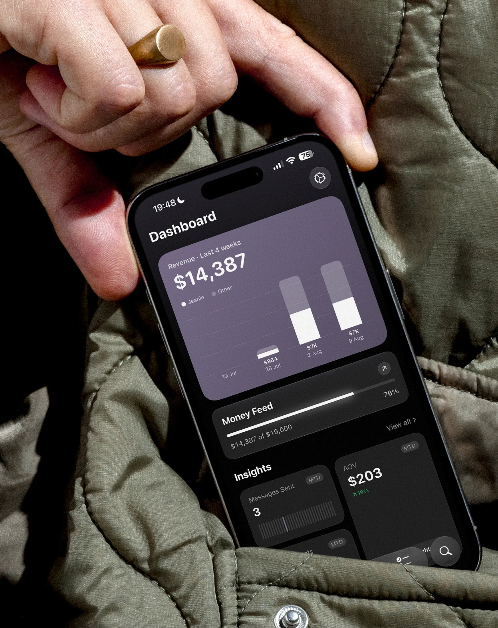 Jeanie's dashboard on a phone held in one hand - four weeks of revenue, the Money Feed against its target, and the insights below it