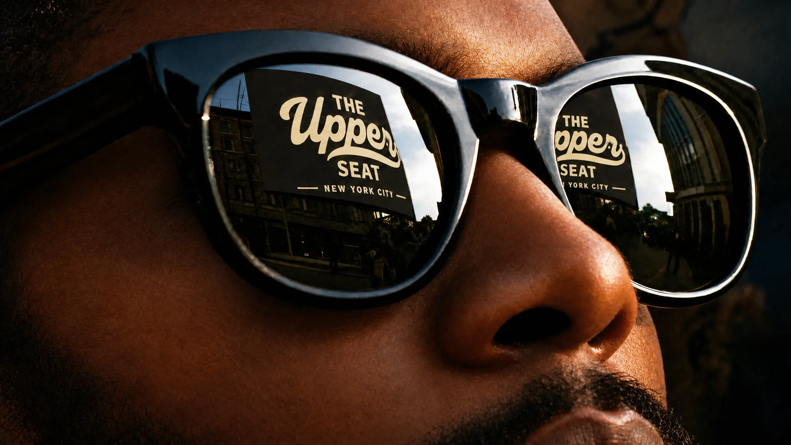 The Upper Seat shopfront sign in New York City, reflected in a client's sunglasses